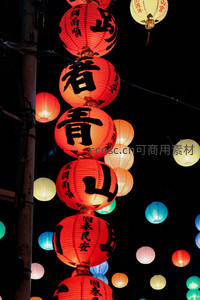 夜市悬挂红灯笼串，黑底衬托传统书法与彩灯辉映节日喜庆氛围