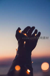 手掌托举串灯迎向暮色天空，指尖星光与渐变晚霞构成诗意剪影