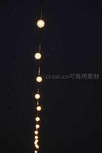 垂直悬挂暖光球形串灯延伸夜空，微尘飘浮中营造静谧梦幻光轨效果