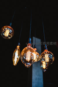 多款复古爱迪生灯泡悬垂于暗背景中，暖黄光丝清晰可见，工业风十足