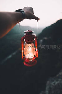 手持复古红煤油灯俯瞰山谷，暮色中光影交织静谧悠远