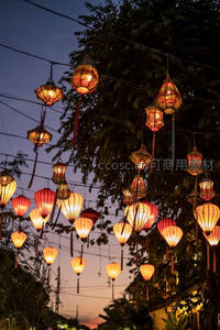 黄昏街巷挂满彩灯，暖光交织绿树与电线，诗意人间烟火