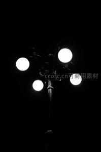 夜幕下古典四头路灯特写，黑白高对比凸显金属结构与光球