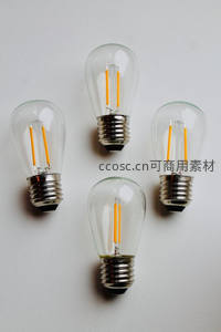 四款不同造型LED灯泡平铺白底，金属螺口与橙色灯丝对比鲜明