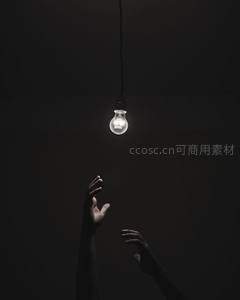 黑暗中双手仰望唯一亮起的灯泡，象征希望与灵感追寻
