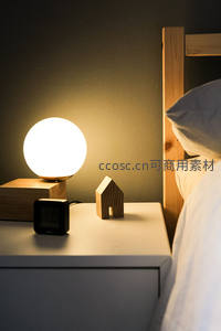 球形床头灯夜景特写，暖光映照木质床架与小屋摆件