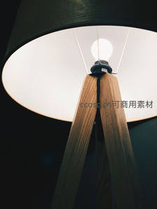 木质三脚架台灯特写，暖光透过白色灯罩柔和漫射