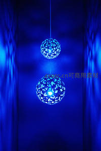 蓝色镂空球形吊灯悬浮于幽暗空间，投射几何光影