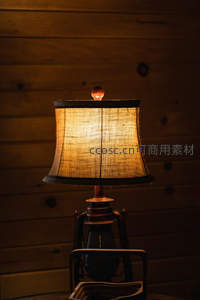 木质背景下的麻布灯罩台灯，暖光映衬原木纹理营造质朴乡村风情