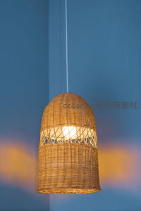 藤编灯笼吊灯悬于蓝墙前，自然光线下展现手工编织纹理与温暖光效