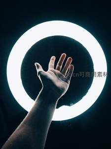 手掌伸向发光环形灯，冷白光晕衬托肌肤纹理，科技感与人文姿态交融