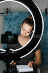 女博主在环形灯前专注阅读脚本，准备视频拍摄内容