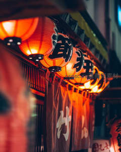 夜市日式纸灯笼串挂街檐，暖光映照布帘汉字招牌