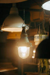 复古工业风吊灯特写，暖光穿透磨砂玻璃罩，营造温馨怀旧氛围