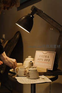 老式台灯照亮茶具促销场景，‘额外40%折扣’标牌增添怀旧商业气息