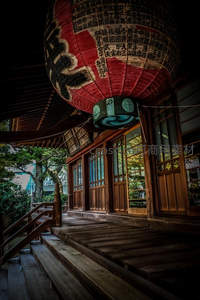 日式寺庙廊下悬挂巨型红黑文字灯笼，木质结构与绿植相映古韵悠长