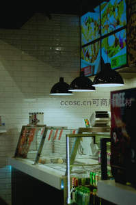 快餐店柜台特写：悬挂黑灯罩、电子菜单屏与冷藏展示柜构成现代餐饮场景