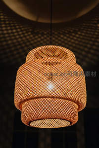 藤编吊灯特写，暖光透出网格纹理，投射几何光影于穹顶之上