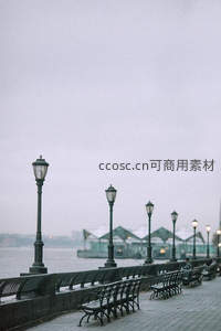 阴雨河畔长廊，空置铁艺长椅与古典路灯静候微光时刻