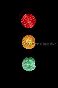 特写交通信号灯三色灯组，红黄绿灯丝交错纹理清晰可见于纯黑背景