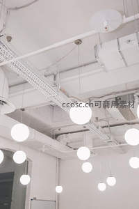 白色球形吊灯悬挂于工业风裸顶天花板，管线裸露，简约现代办公空间照明设计