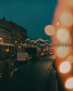 夜幕城市街景，车流与节日灯饰交织，前景光斑梦幻朦胧