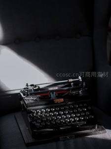 暗调光影中的老式打字机，置于深色软垫座椅，氛围感十足