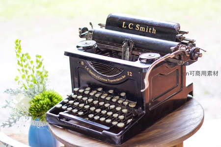 LC Smith古董打字机摆拍于户外木桌，绿植映衬典雅复古风