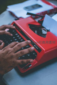 红色便携打字机上双手敲击，现代与复古交融的创作瞬间