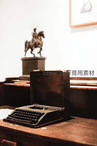 木质书桌上的老式打字机与骑马雕像背景