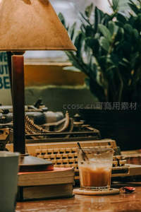 浅景深下的咖啡杯与打字机局部，绿植虚化背景