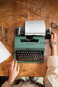 俯拍视角下打字机载纸书写，双手轻抚键盘，桌面文具整齐有序